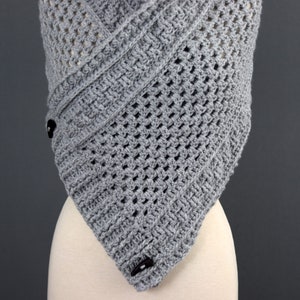 May include: Gray crochet shawl with a geometric pattern and two black buttons.