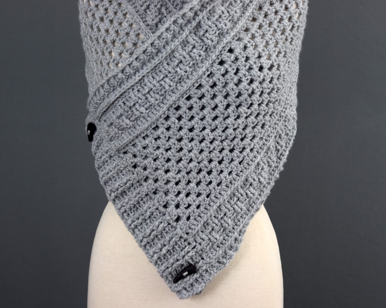 May include: Gray crochet shawl with a geometric pattern and two black buttons.