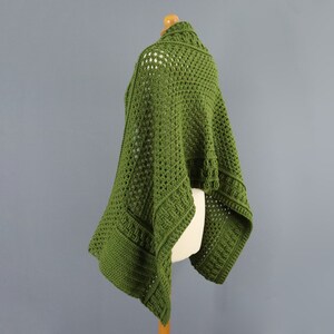 May include: A green crochet shawl with a lacy pattern. The shawl is draped over a dress form.