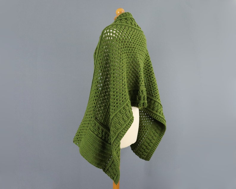 May include: A green crochet shawl with a lacy pattern. The shawl is draped over a dress form.