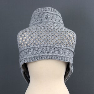 May include: Gray crocheted cowl with a geometric pattern. The cowl is displayed on a white mannequin.