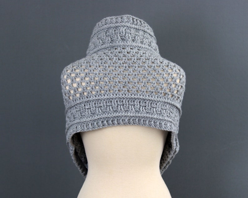 May include: Gray crocheted cowl with a geometric pattern. The cowl is displayed on a white mannequin.