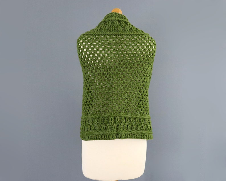 May include: A green crochet vest with a square stitch pattern. The vest is sleeveless and has a wide, open neckline.