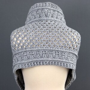 May include: Gray crocheted cowl with a geometric pattern. The cowl is made with a lightweight yarn and has a loose, open weave.