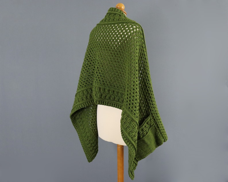 May include: A green crochet shawl with a lacy pattern and a pocket on one side.