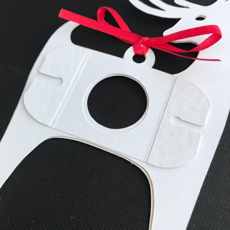 May include: White paper reindeer cutout with a red ribbon bow. The reindeer has a circular hole in the center of its body.