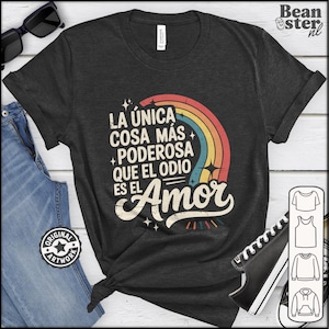 Op de afbeelding: Donkergrijs t-shirt met een regenboogafbeelding en de Spaanse tekst "LA ÚNICA COSA MÁS PODEROSA QUE EL ODIO ES EL Amor". Het shirt wordt gecombineerd met een spijkerbroek en sneakers. Gemaakt van een zacht, comfortabel materiaal.