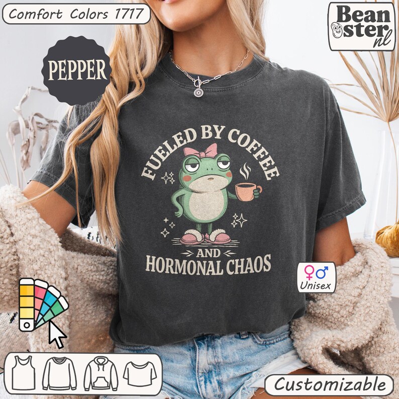 Pu&ograve; includere: T-shirt unisex grigio scuro con grafica a rana con tazza di caff&egrave;. Il testo recita "Fueled by Coffee and Hormonal Chaos". La maglietta &egrave; personalizzabile e realizzata in materiale Comfort Colors 1717. Il colore &egrave; Pepper.