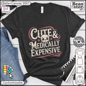 Op de afbeelding: Donkergrijs unisex T-shirt met de tekst "Cute & Medically Expensive" in een roze en wit ontwerp. Het shirt heeft een schedelafbeelding en is aanpasbaar.