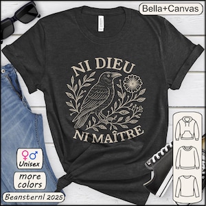 Op de afbeelding: Donkergrijs unisex T-shirt met een crème raven illustratie en de Franse tekst "Ni Dieu Ni Maître". Het shirt is van Bella+Canvas en heeft extra kleuropties. Het ontwerp bevat bloemmotieven.
