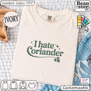 May include: Ivory-colored t-shirt with the text "I hate Coriander" in green. The shirt is a Comfort Colors 1717 model and is labeled as unisex and customizable. Additional design options are shown at the bottom of the image.
