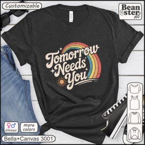 May include: Dark gray unisex t-shirt with the text "Tomorrow Needs You" in a retro design featuring a rainbow and sun. The shirt is made of Bella+Canvas 3001 material and is customizable.