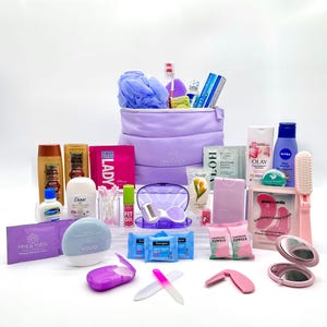 May include: A collection of beauty and personal care products, including a lavender cosmetic bag, shampoo, conditioner, skincare, makeup remover wipes, and a toothbrush. Other items include a nail file, compact mirror, and compressed towels.
