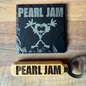 May include: A black slate coaster and a wooden bottle opener, both featuring the band name "Pearl Jam". The coaster has the band's logo. The bottle opener has a silver metal opener.