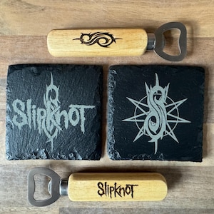 May include: A collection of bar accessories, including a wooden bottle opener and black slate coasters. The bottle openers have a metal opener and a wooden handle with a logo. The square coasters feature a logo and the band name.
