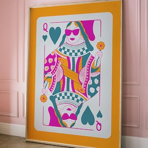 Op de afbeelding: Een illustratie van de speelkaart Koningin van Schoppen, met een kleurrijk, geometrisch ontwerp. De koningin draagt een zonnebril en houdt een bloem vast. De kaart is geplaatst tegen een feloranje achtergrond.