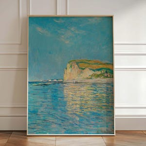 May include: A painting of a seascape with a large white cliff in the distance. The water is a light blue and the sky is a pale blue. The painting is in a light wood frame.