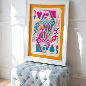 May include: A framed print of a Queen of Hearts playing card with a colorful design. The Queen is wearing sunglasses and holding a glass of champagne. The background is a bright orange color.