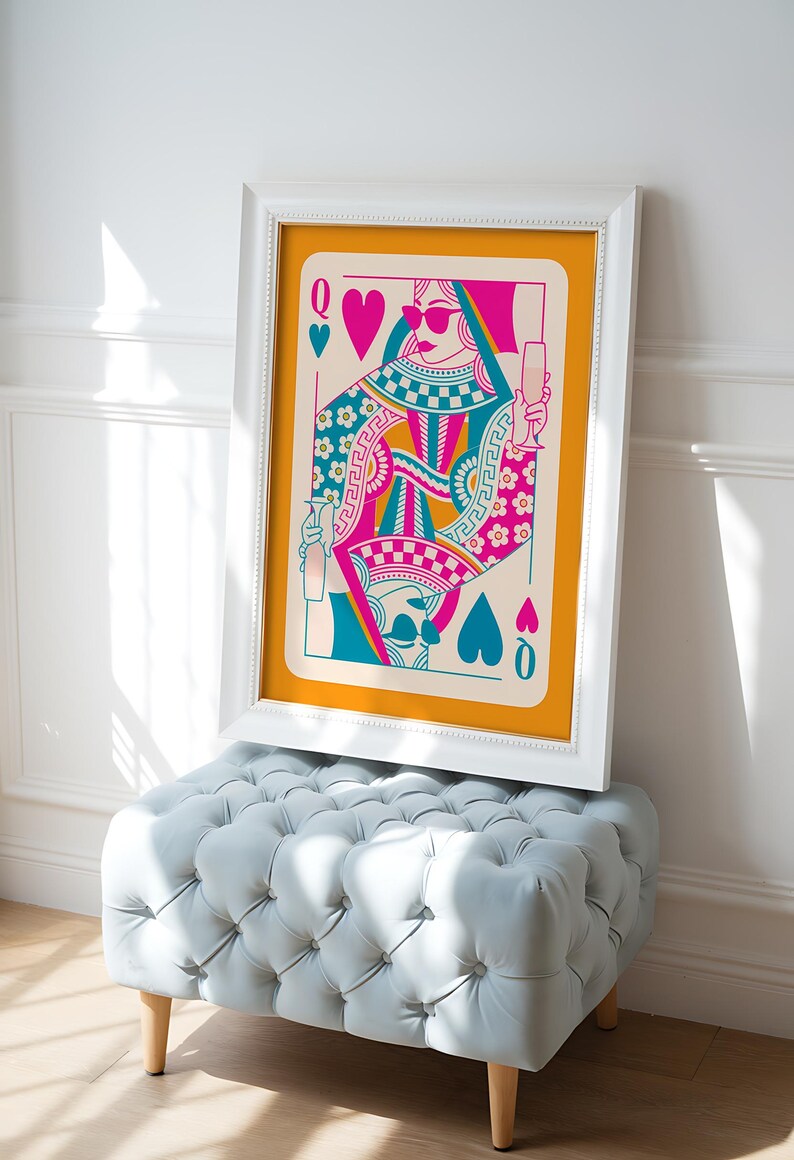 May include: A framed print of a Queen of Hearts playing card with a colorful design. The Queen is wearing sunglasses and holding a glass of champagne. The background is a bright orange color.