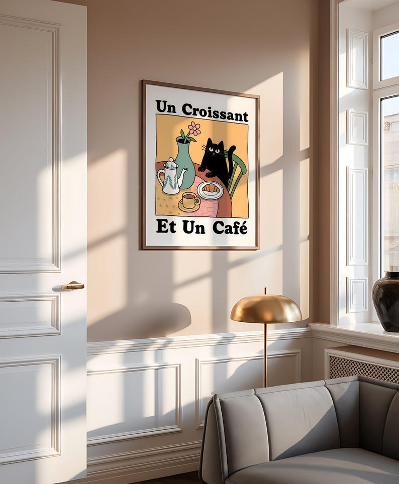 May include: A black cat sits at a table with a cup of coffee, a croissant, and a teapot. The text on the poster reads "Un Croissant Et Un Caf&eacute;".