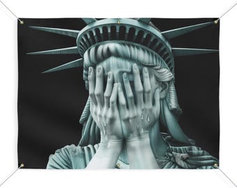 May include: A statue of the Statue of Liberty with her hands covering her face and tears running down her cheeks. The statue is against a black background.