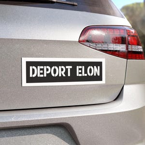 May include: A silver car with a black and white bumper sticker that reads "DEPORT ELON".