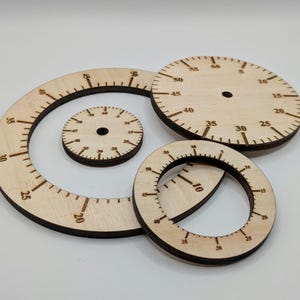 Puede incluir: Tres transportadores de madera con diferentes tamaños y marcas. El transportador más grande tiene marcas del 5 al 60, el transportador del medio tiene marcas del 5 al 60 y el transportador más pequeño tiene marcas del 5 al 60.