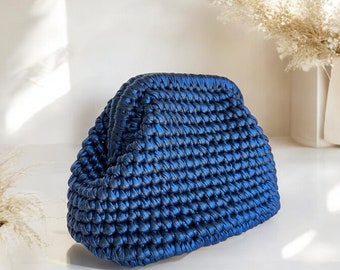 May include: A blue woven clutch bag with a textured surface. The bag has a rounded shape and a slightly domed top.
