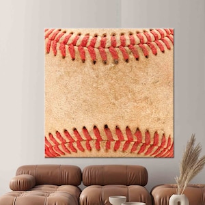 May include: Close-up of a worn baseball with red stitching. The leather is textured and shows signs of use.