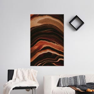 May include: Abstract art print with a flowing, layered design in shades of brown, rust, and black. The artwork resembles natural stone or geological formations. The rectangular canvas is mounted on a white wall.