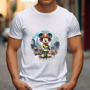 May include: White t-shirt with a watercolor illustration of Mickey Mouse dressed as a firefighter. Mickey is standing in front of a cityscape with fire trucks in the background.