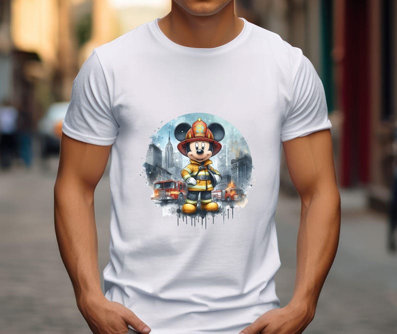 May include: White t-shirt with a watercolor illustration of Mickey Mouse dressed as a firefighter. Mickey is standing in front of a cityscape with fire trucks in the background.