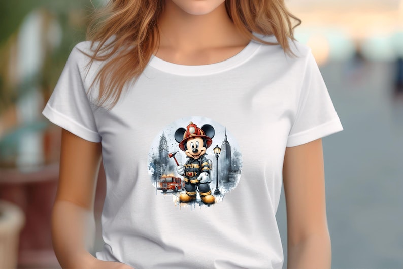 May include: White t-shirt with a graphic of Mickey Mouse dressed as a firefighter in front of a city skyline. The graphic is in a watercolor style.