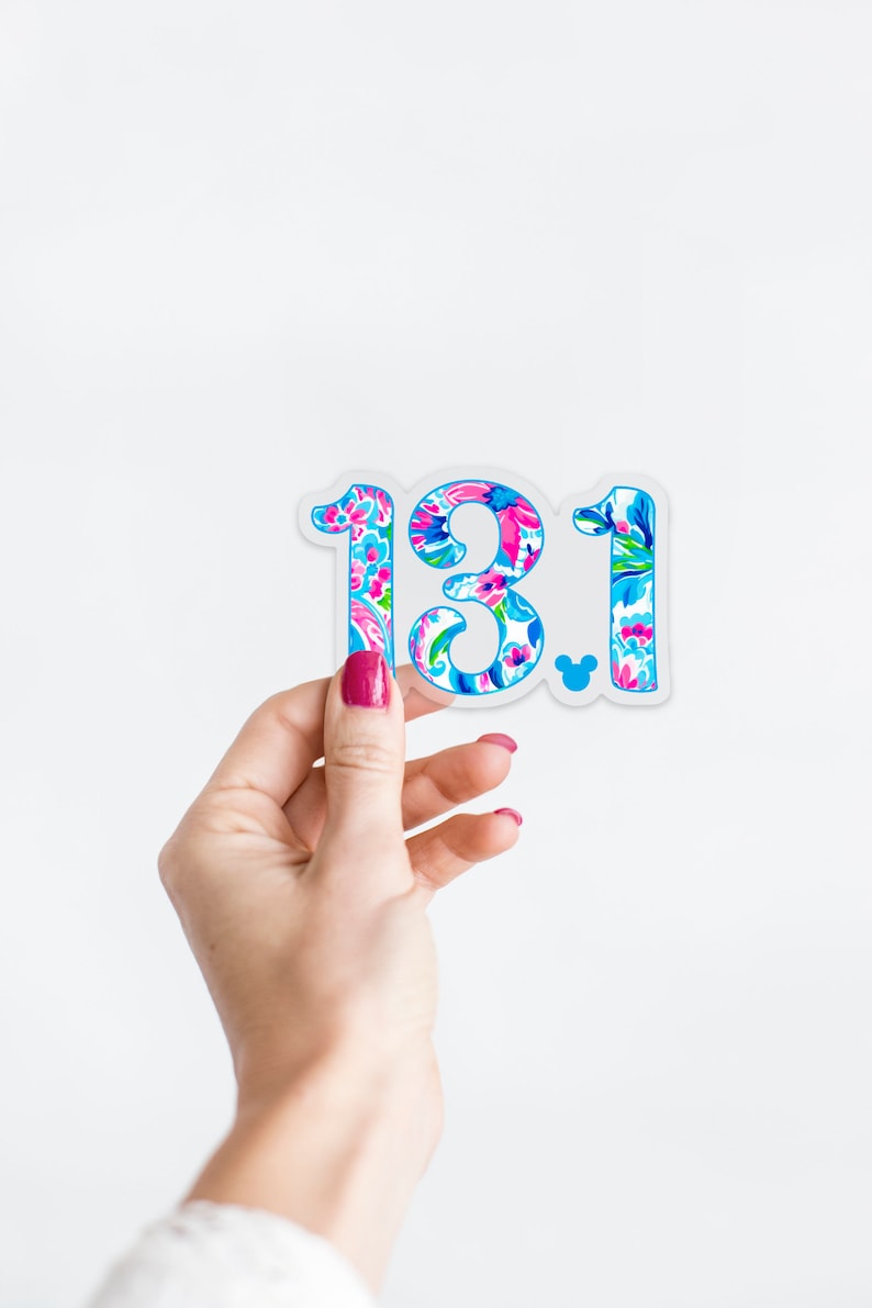 Puede incluir: Una pegatina transparente con un patr&oacute;n floral en tonos de rosa, azul y verde. La pegatina presenta el n&uacute;mero "13.1" con un peque&ntilde;o icono de Mickey Mouse.