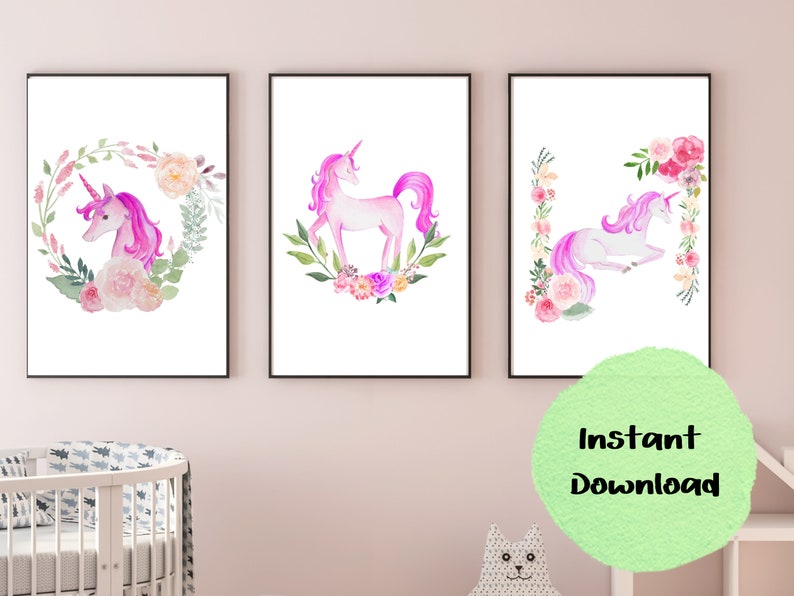 May include: Three printable wall art prints featuring watercolor illustrations of unicorns with floral wreaths. The unicorns are pink and white with pink manes and tails. The floral wreaths are pink, white, and green.