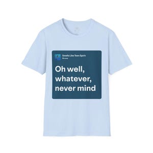 Könnte beinhalten: Ein hellblaues T-Shirt mit kurzen Ärmeln und einer dunkelblauen quadratischen Grafik auf der Brust. Die Grafik zeigt den Text "Smells Like Teen Spirit", "Nirvana" und die Liedzeile "Oh well, whatever, never mind" in weißer, serifenloser Schrift.