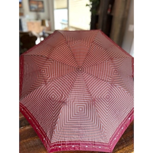 以下が含まれることがあります： 黒い持ち手と「But First, Coffee」の太字の黒い文字が入った白いセラミックマグ。マグカップはぼやけた背景に置かれています。マグカップの高さは約10cmです。