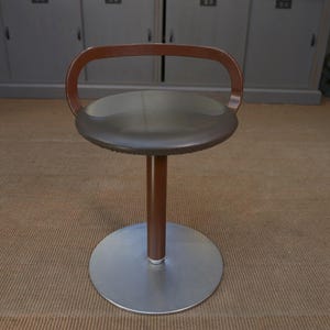 Peut inclure: Un tabouret de bar pivotant en cuir marron avec une base en métal et un dossier en bois.