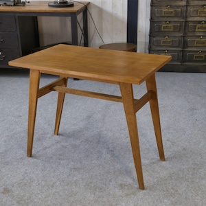 May include: A small, rectangular wooden table with a light brown finish. The table has four angled legs and a supporting crossbar. The table is approximately 24 inches long, 16 inches wide, and 28 inches tall.