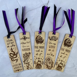 May include: Five wooden bookmarks with black and purple ribbons. Each bookmark features engraved designs and text, including a snake, moon phases, and phrases like "Witches are witches do" and "The moon made me do it."