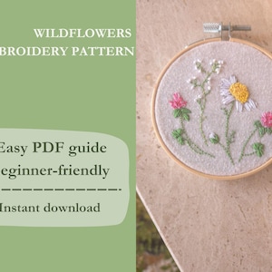 Può includere: Un telaio da ricamo con un disegno floreale, tra cui una margherita, trifoglio e altri fiori selvatici. Il testo a sinistra recita "WILDFLOWERS EMBROIDERY PATTERN" e "Easy PDF guide beginner-friendly Instant download".
