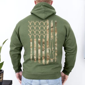 Camo flag hoodie showing love for hunting and the USA, worn at gun ranges or hunting lodges.