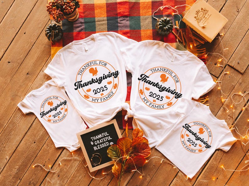 May include: White t-shirts with a Thanksgiving design. Each shirt displays a circular graphic with a turkey, the text "Thankful for Thanksgiving 2025 My Family", and autumn leaves. A small chalkboard reads "Thankful, Grateful, Blessed".