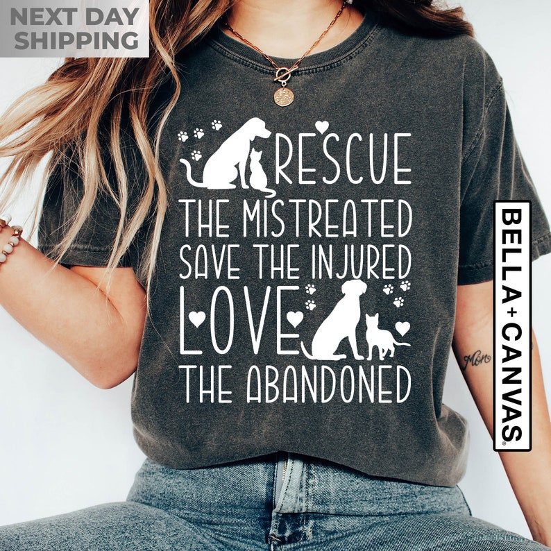May include: A dark gray t-shirt with a white graphic design featuring a dog and cat silhouettes. The text reads "Rescue the mistreated, save the injured, love the abandoned".
