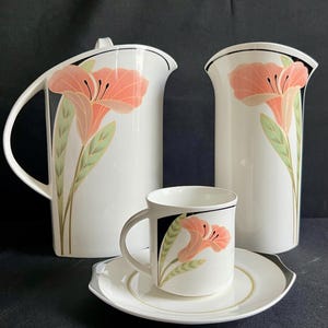 May include: A set of three ceramic mugs with a speckled, matte finish. The mugs are in shades of cream, light gray, and dark gray. Each mug has a simple, modern design and a rounded handle.