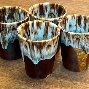 May include: Set of four brown and white ceramic mugs with a drip glaze design. The mugs are all the same size and shape.