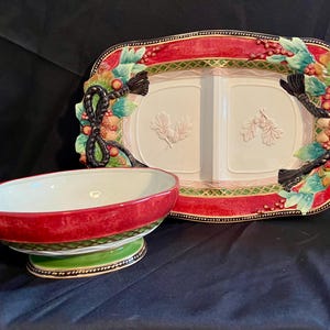 May include: A decorative serving set featuring a divided rectangular platter and a matching oval bowl. The set has a red and green color scheme with embossed floral and berry accents. The platter has a central divider.