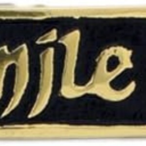 May include: A rectangular brass plaque with the Gaelic phrase "céad míle fáilte" in gold lettering on a black background. The plaque has rounded ends with holes for mounting.