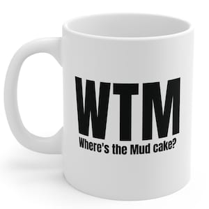 May include: White ceramic mug with a black "WTM" graphic and the text "Where's the Mud cake?" printed on the front. The mug has a curved handle and is suitable for hot or cold beverages.