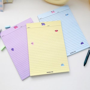 May include: Three lined notepads with different colored covers: purple, yellow, and blue. Each notepad has a rainbow dog illustration on the bottom right corner and the text "Rainbow Dog".